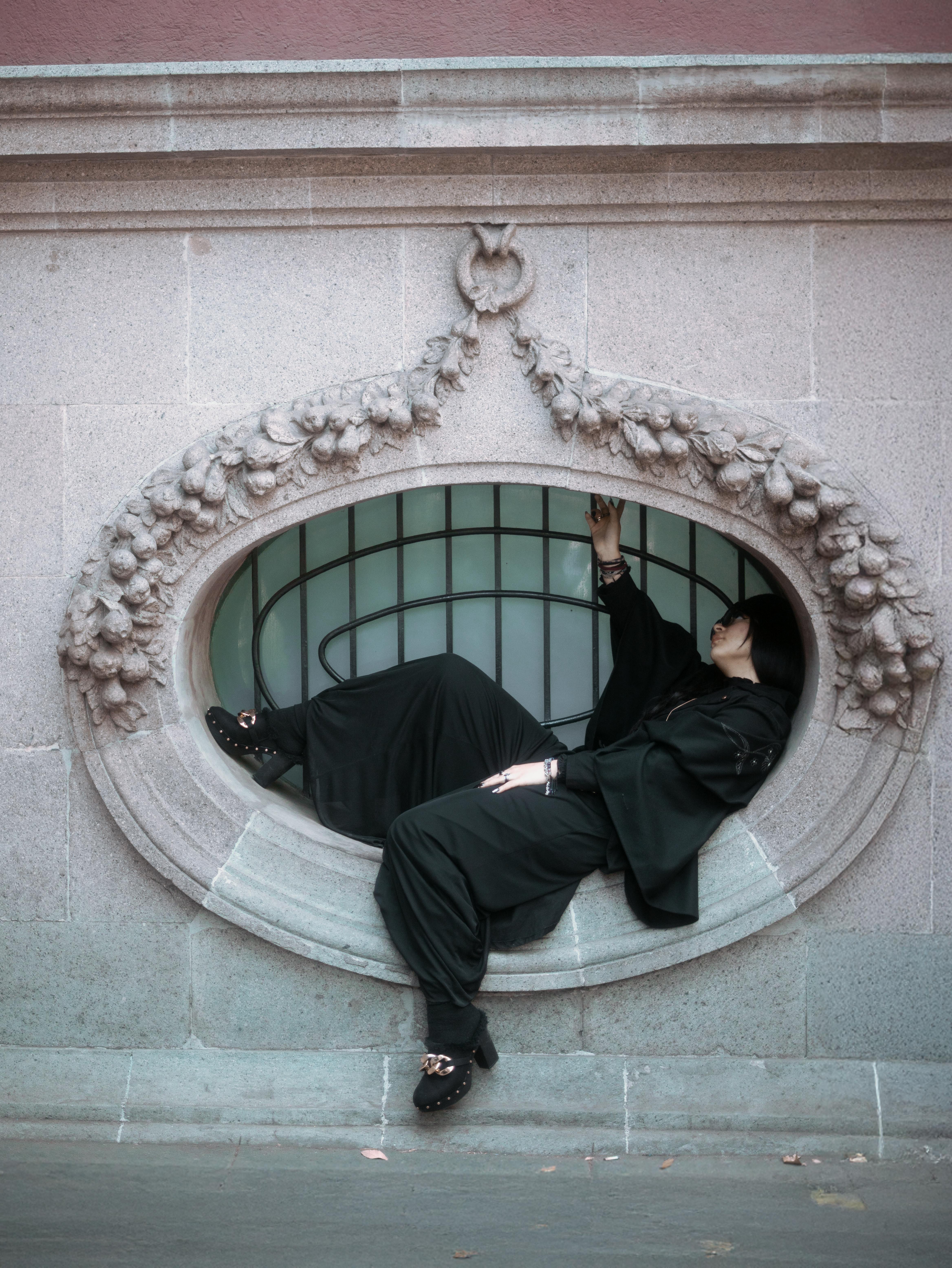 Free Elegant fashion portrait in an ornate window frame in Mexico City, showcasing urban style. Stock Photo