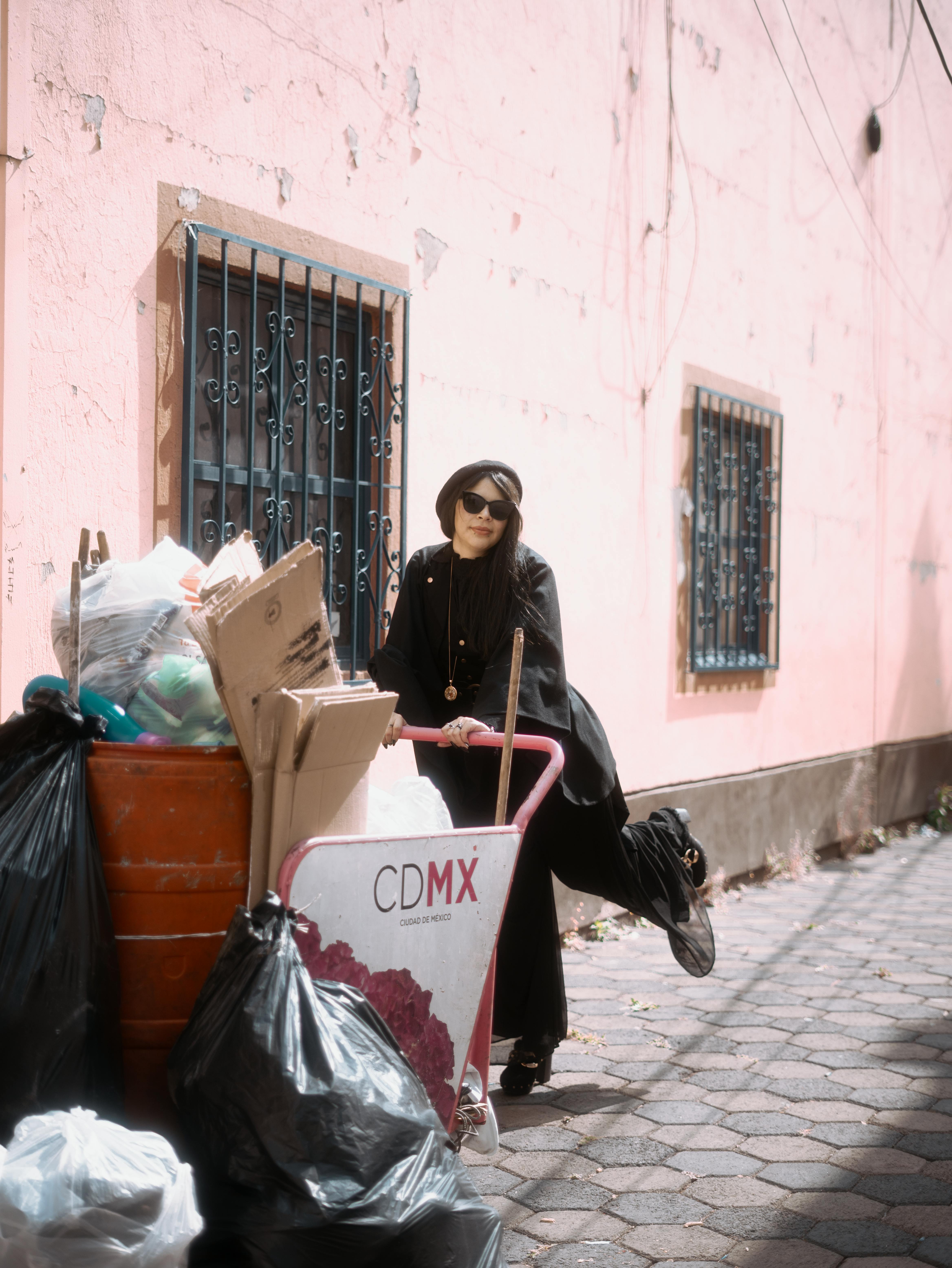 Zadarmo Štýlová žena v čiernom oblečení pózuje pri odpadkovom koši v Condese v Mexico City. Fotka z fotobanky