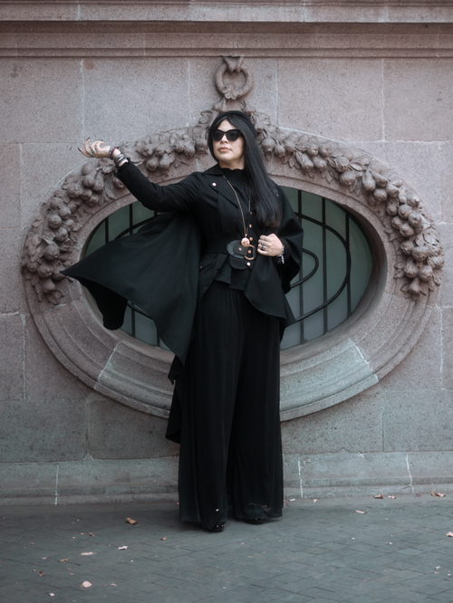 Free Stylish woman in black fashion attire posing elegantly against a classic stone backdrop in Mexico City. Stock Photo