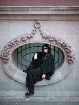Stylish woman in a black dress and sunglasses poses elegantly in Mexico City's historic architecture.