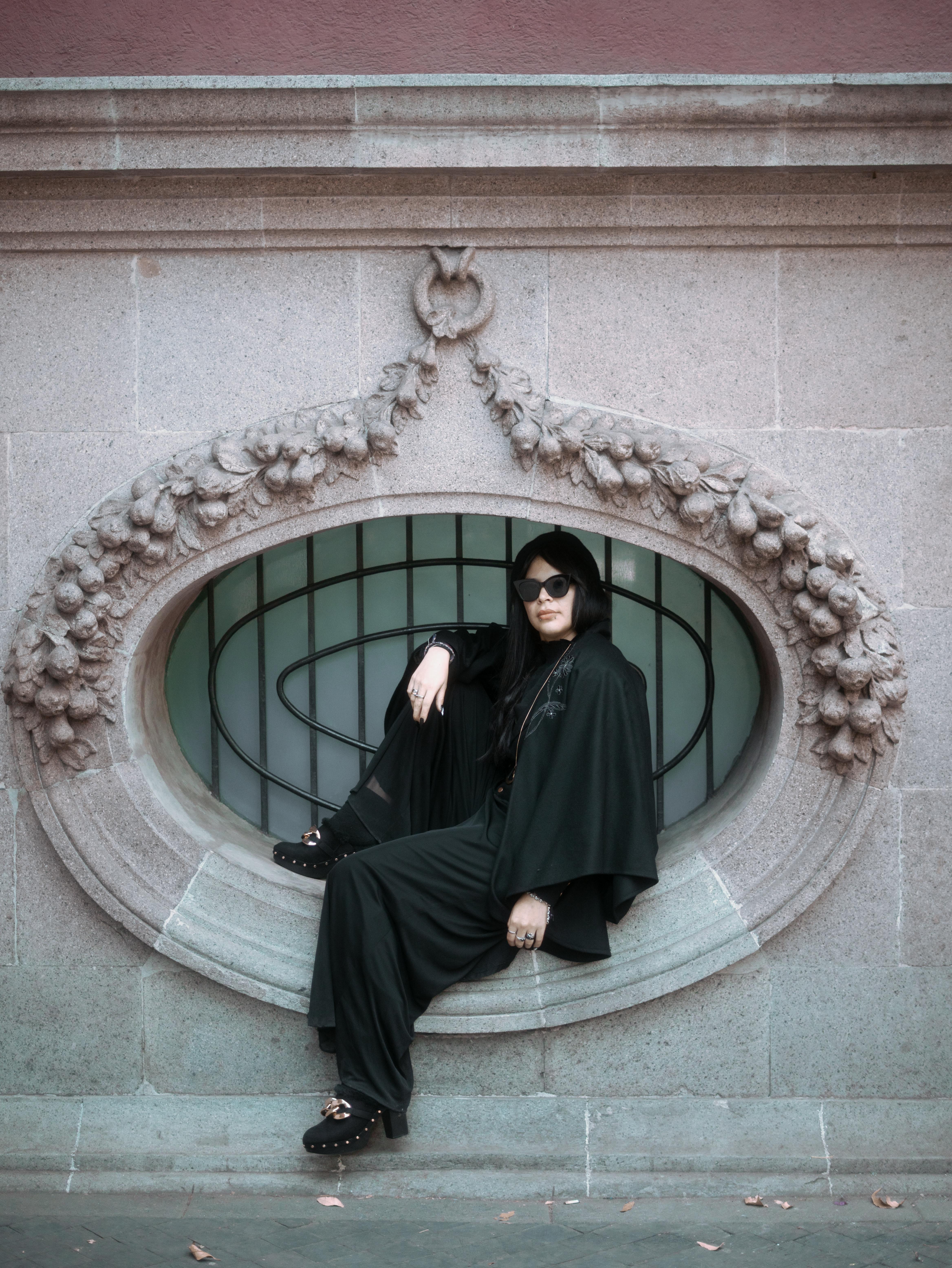 Free Stylish woman in a black dress and sunglasses poses elegantly in Mexico City's historic architecture. Stock Photo