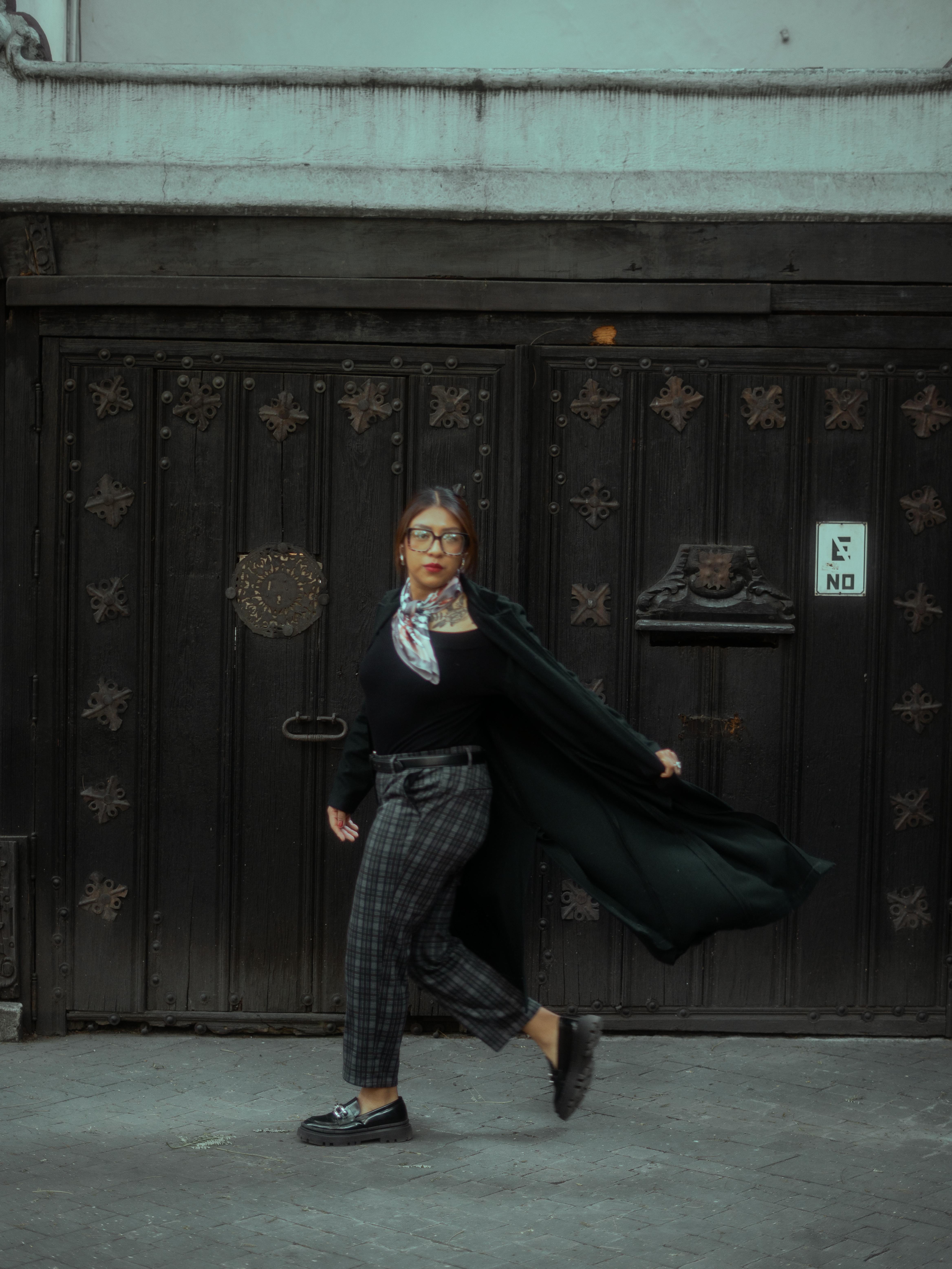 Gratis Una donna elegante in abito scuro posa contro una porta d'epoca a Città del Messico. Foto a disposizione