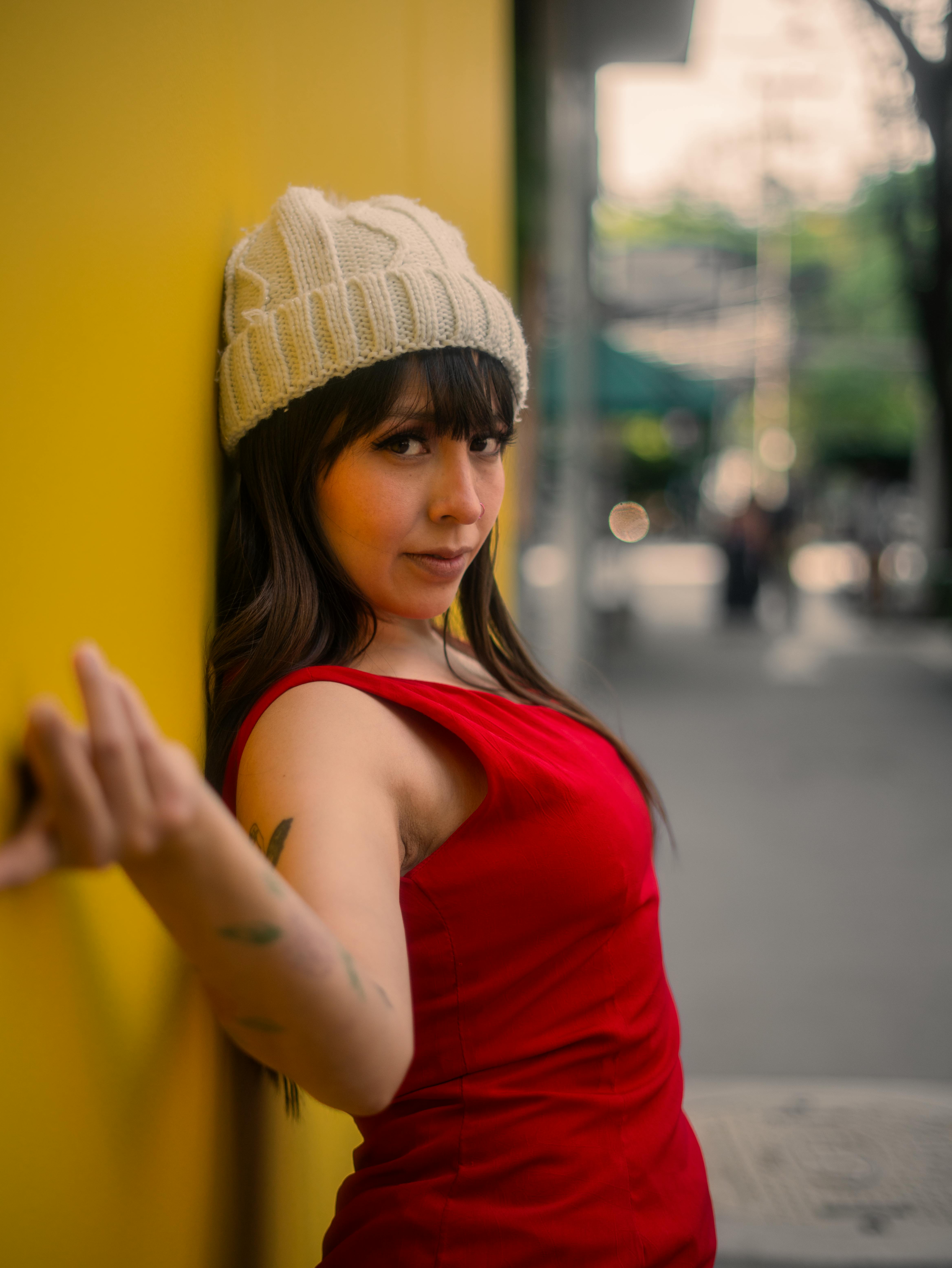 gratis Stijlvolle vrouw in rode jurk en muts poseert tegen een gele muur in Mexico-Stad. Stockfoto