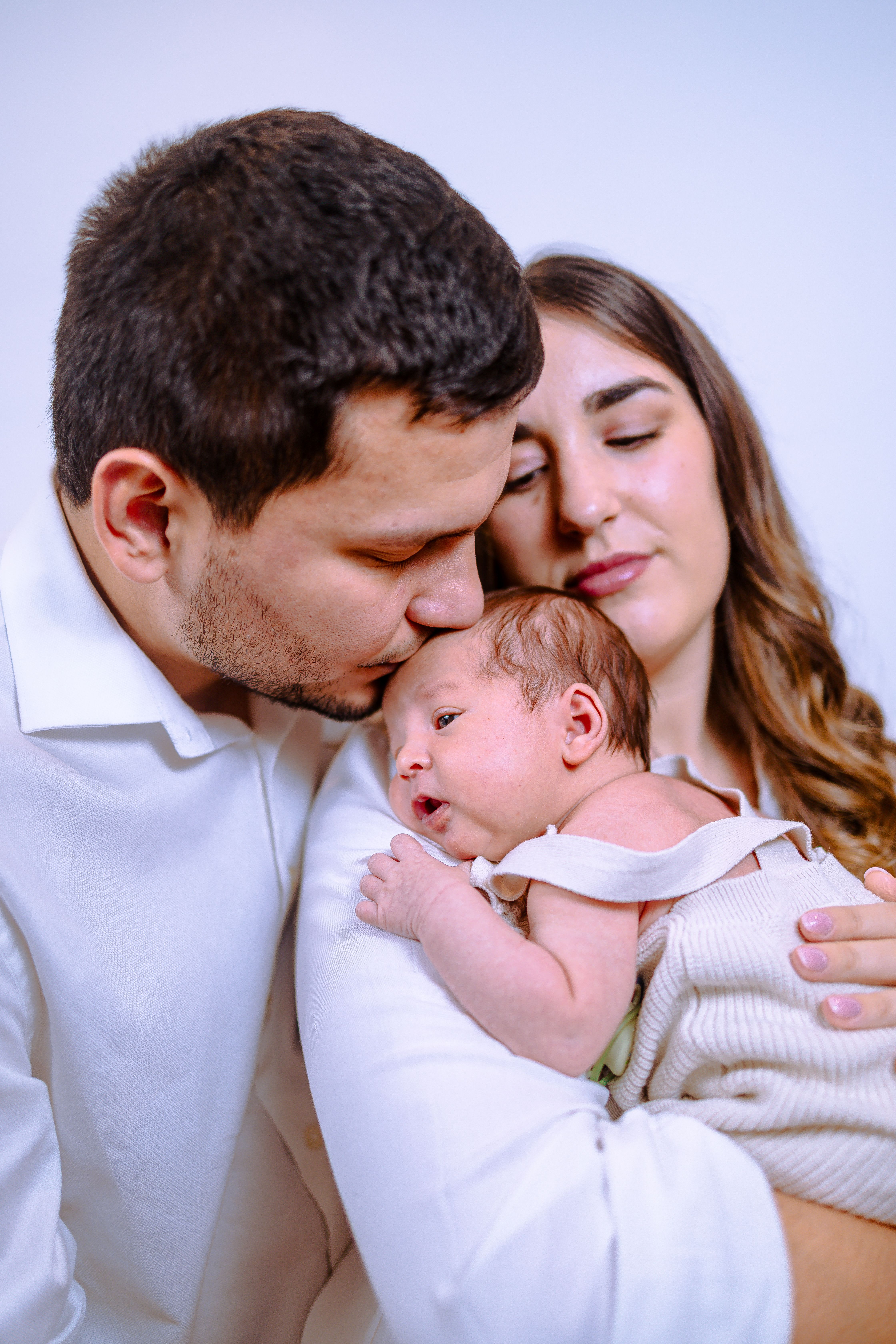 Tender moment of a couple embracing their newborn baby with love and warmth.