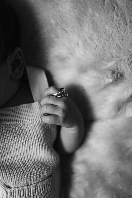 Free An artistic shot of a baby's hand holding a ring on a soft surface. Stock Photo
