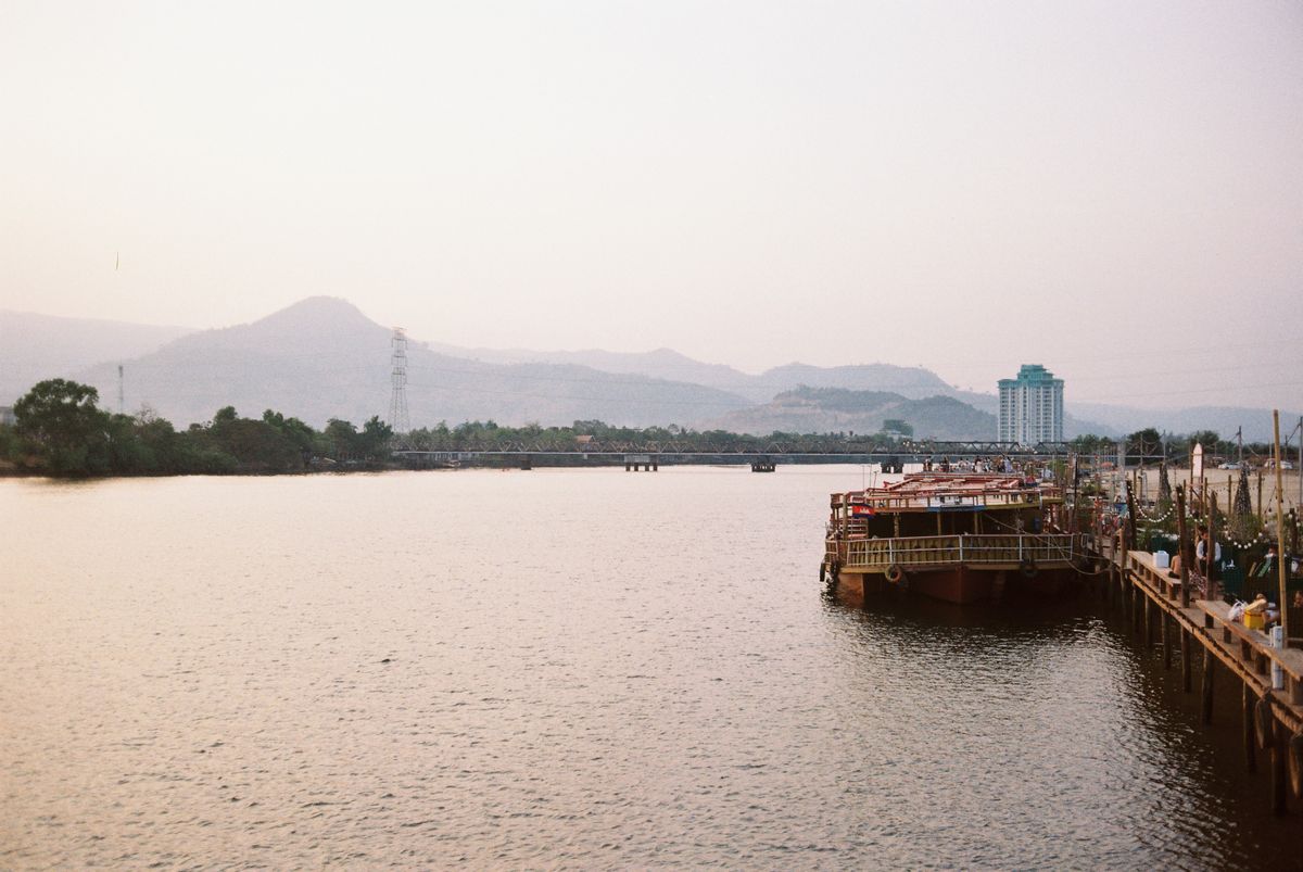 Boats on the Kampot River at dusk with hills in the distance