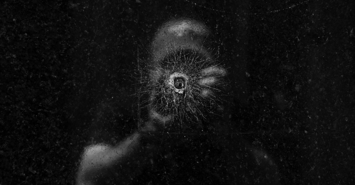 Remove Scratches from Glasses: 8 Products That Actually Work 3 Artistic photograph of a person's reflection seen through a bullet hole on a dark glass surface. - remove scratches from glasses