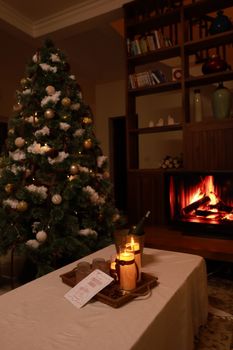 Warm living room with decorated Christmas tree, fireplace, and candles setting a festive mood.
