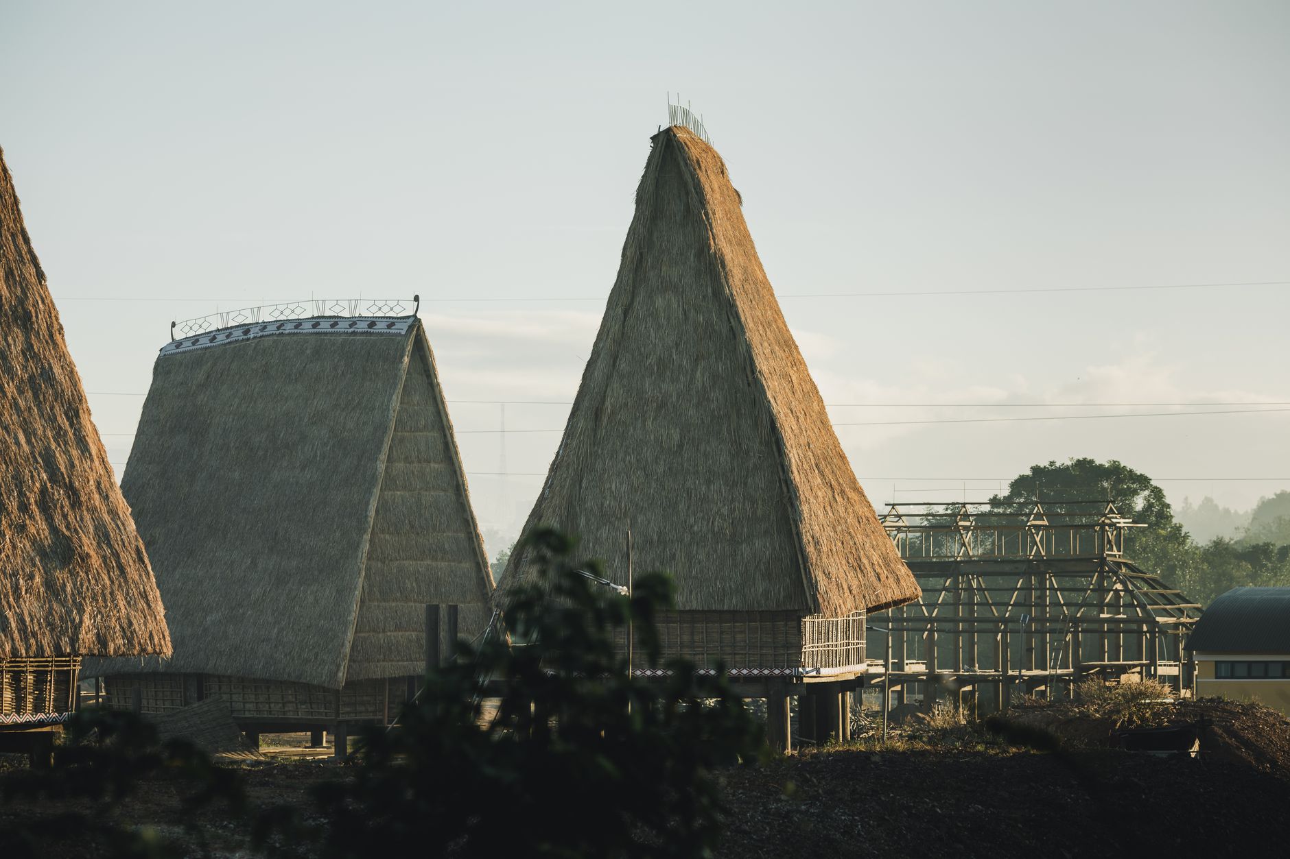 Stunning view of traditional thatched roof houses in Kon Tum, Vietnam under early morning light.