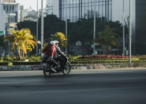 Free Two adults riding a motorbike on a street in Kon Tum, Vietnam, capturing urban life. Stock Photo