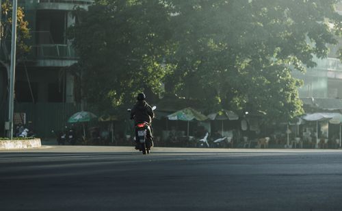Free A person on a motorcycle drives through a quiet street in Kon Tum, Vietnam, during early morning light. Stock Photo