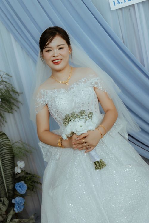 Free Smiling bride in a sparkling white wedding gown holding flowers. Stock Photo