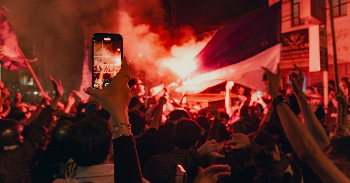 protest crowd holding smartphones with flashlights in dark city street