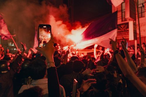 Free A lively crowd gathers at night with flags and flares, capturing the event on smartphones in Bandung. Stock Photo