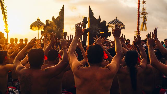 Peserta merangkul budaya Bali saat menari Kecak saat matahari terbenam di Bali, Indonesia.