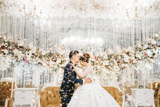 Couple kissing at a lavish wedding with floral decor in West Java, Indonesia.