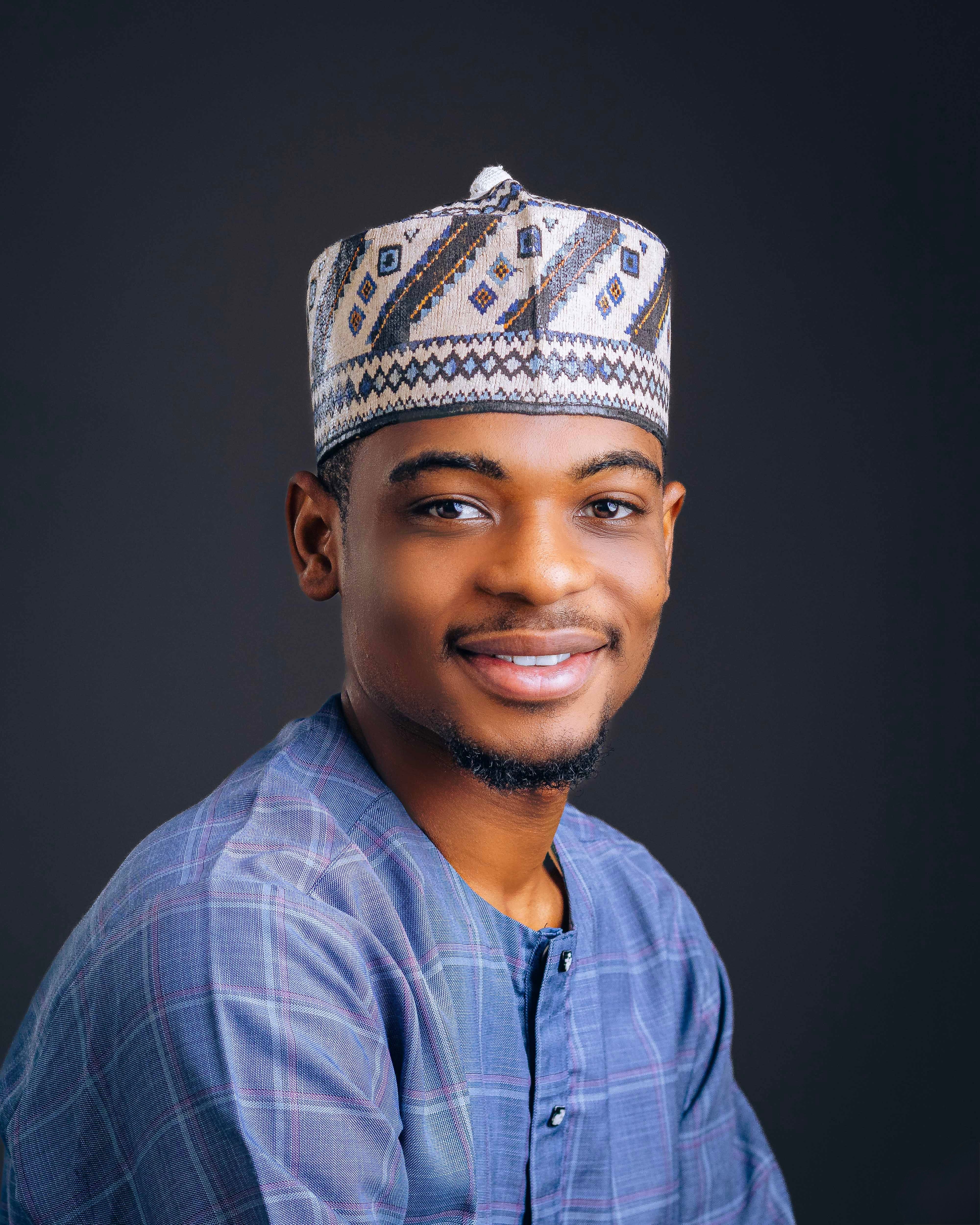 Confident young man wearing cultural attire with a friendly smile in a studio portrait.