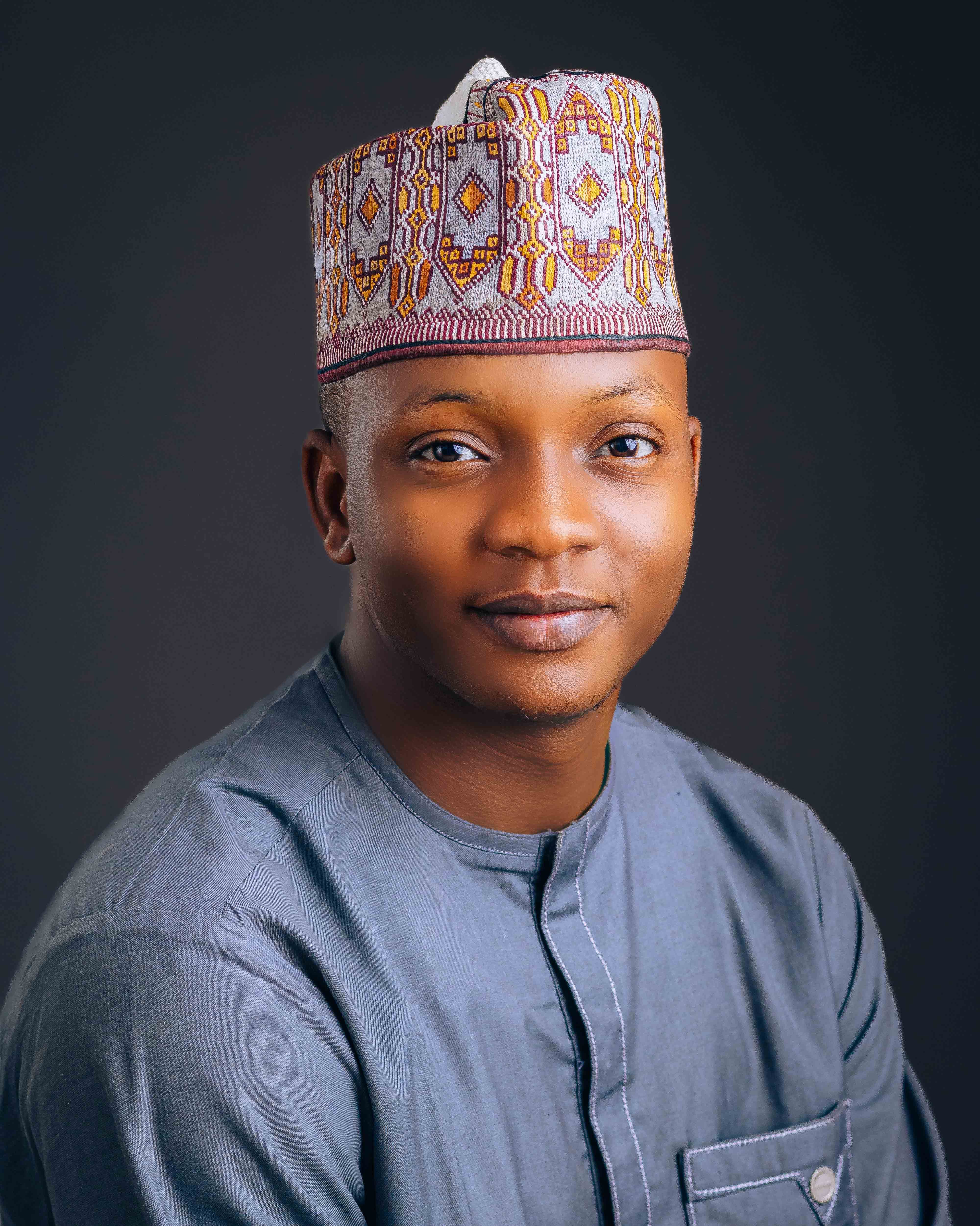 Smiling man wearing traditional attire with embroidered hat, posing confidently.
