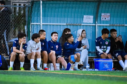 A group of young soccer players taking a break and chatting on the sidelines during a match in Hà Nội, Vietnam.