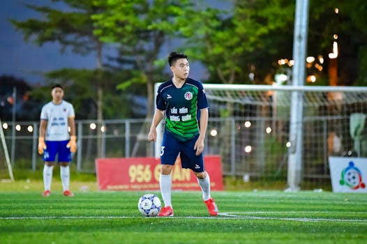 Photo by ANH LÊ Live football match in Hà Nội with players in dynamic action under stadium lights.