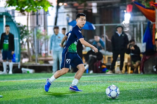 A soccer player dynamically dribbling the ball during an outdoor match in Hà Nội, Việt Nam.