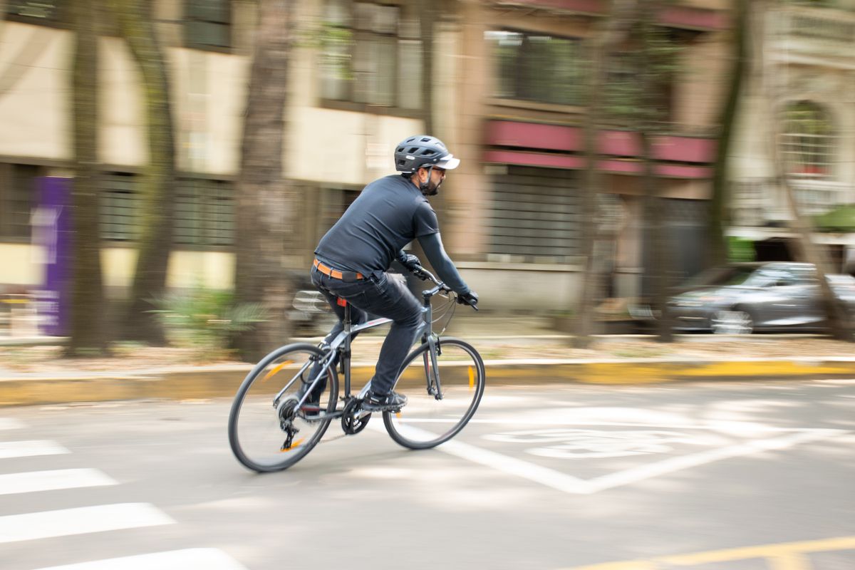 Helmeted cyclist riding through a modern urban street