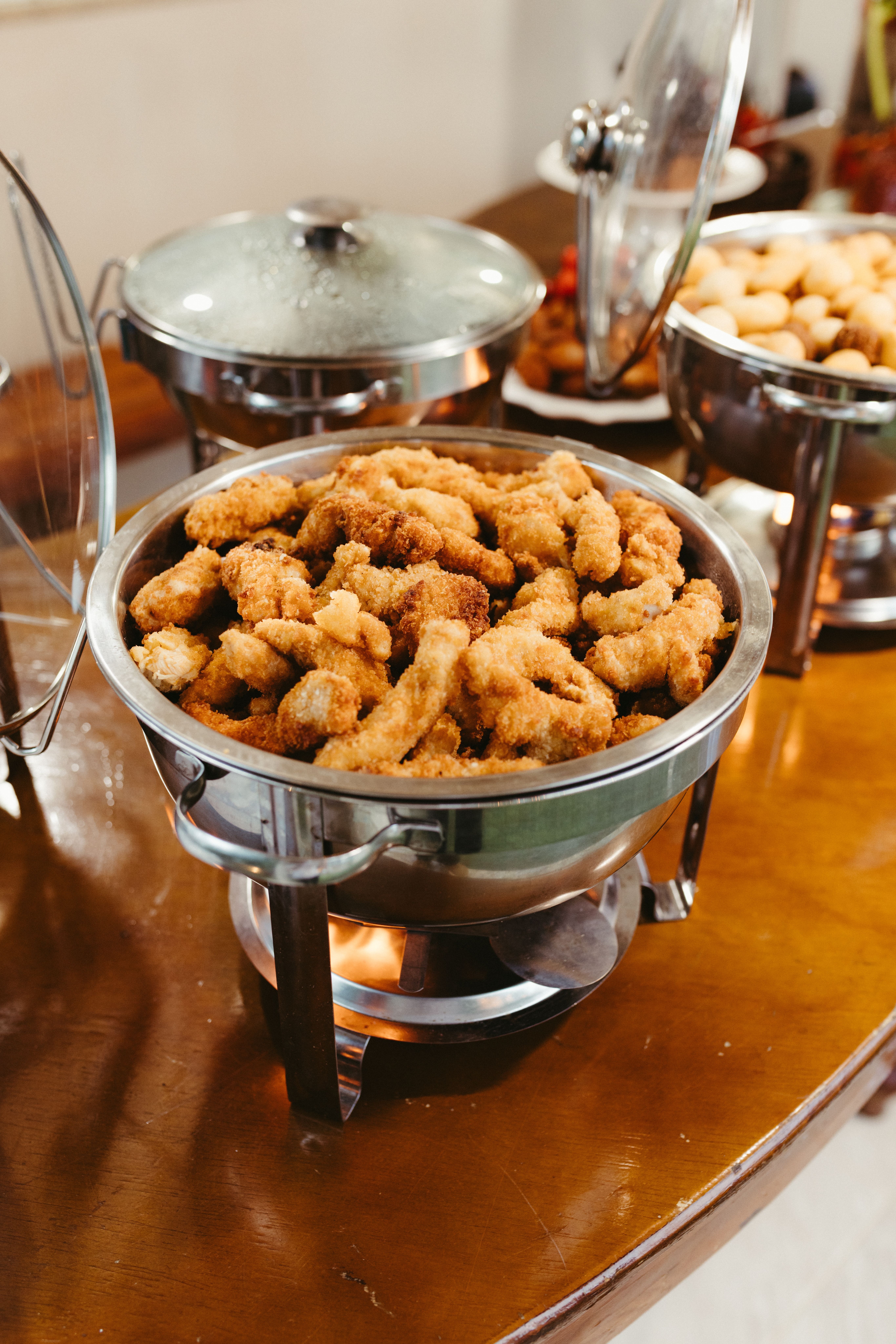 Crispy fried food served in a chafing dish at a buffet setup, offering warm meal options.