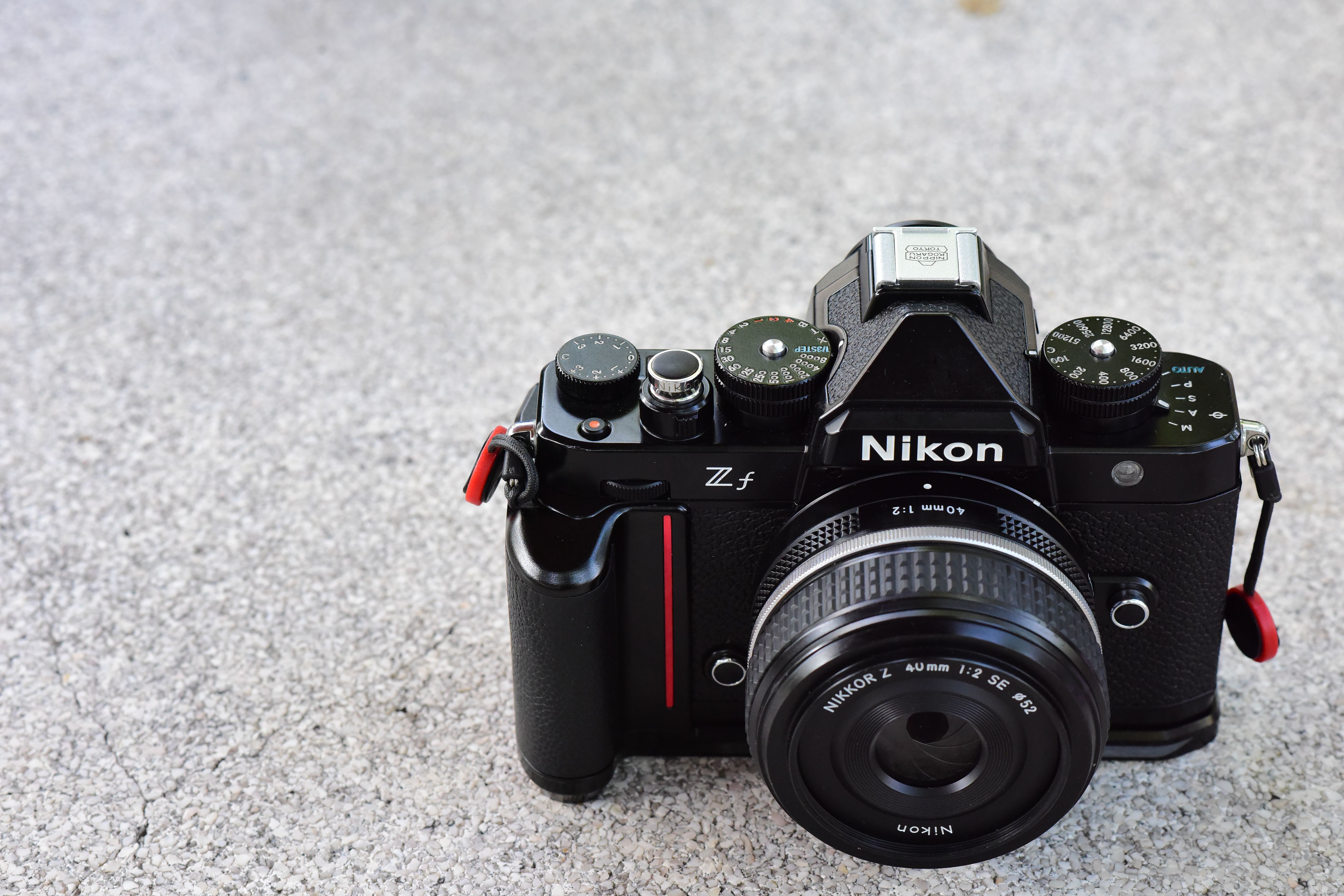 Close-up of a vintage-style Nikon camera on a textured gray surface.