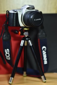 A professional DSLR camera mounted on a tripod in a studio environment with blurred background.