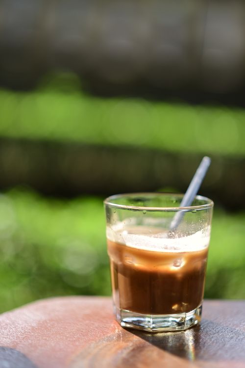 Free Glass of iced coffee with straw on a table outside, enjoying a sunny day. Stock Photo