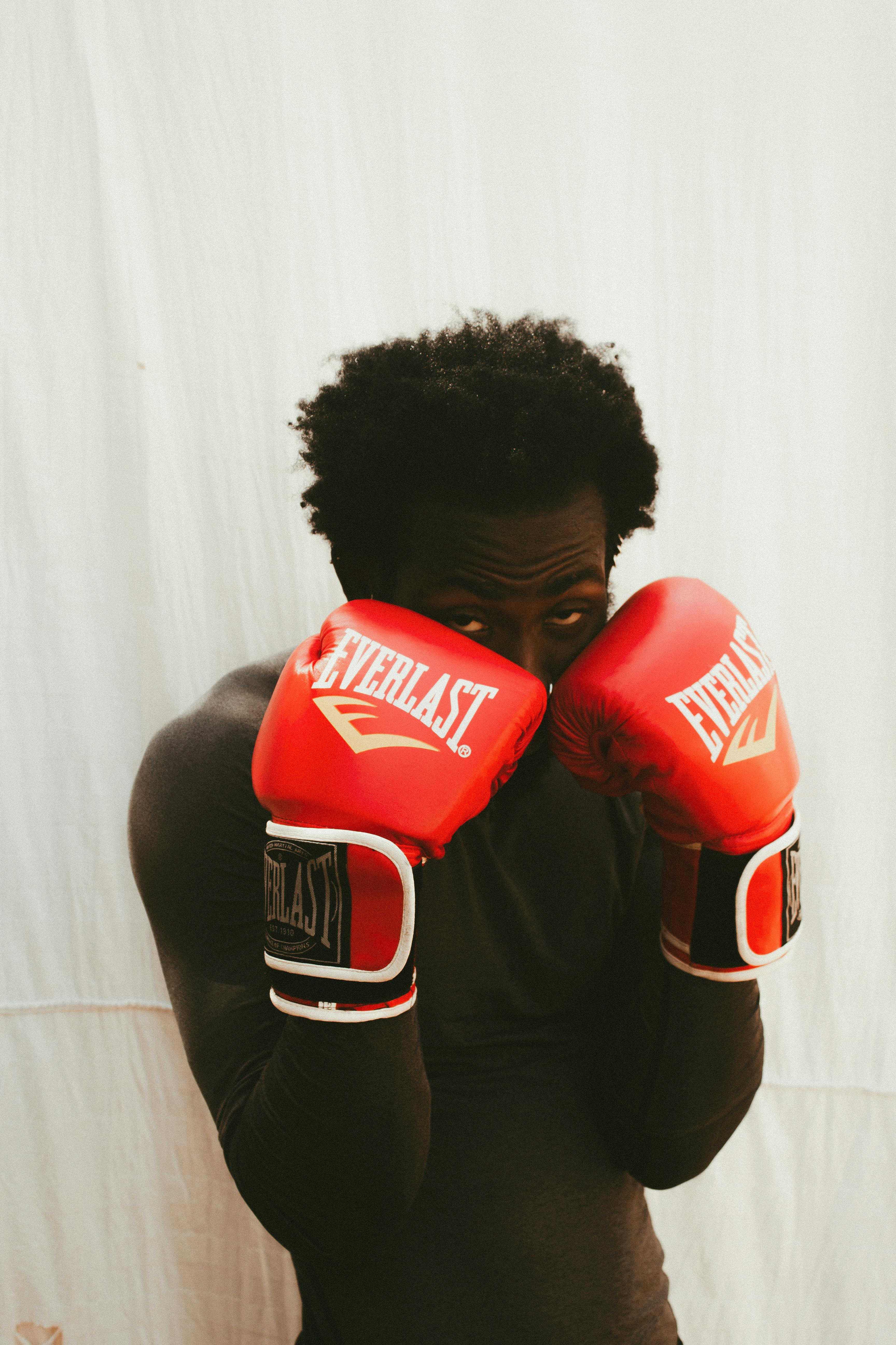 Portrait of a black male boxer wearing red gloves. Intense focus and determination.