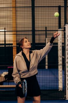 Female tennis player preparing to serve during an indoor match.