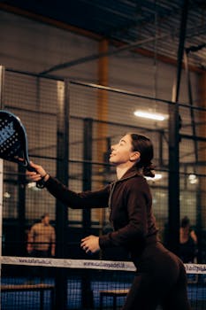 Female athlete playing padel tennis indoors, showcasing focus and movement.