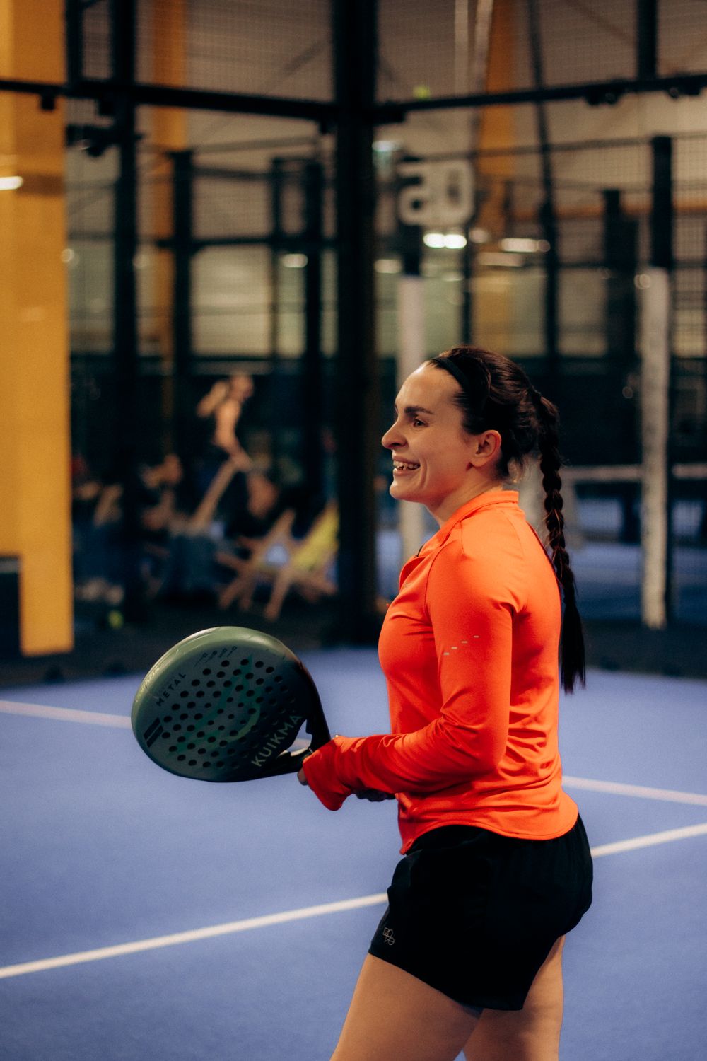 Padel-Spielerin beim Schlag auf blauem Indoor-Court