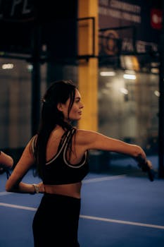A young woman in activewear engaging in a fitness routine in an indoor sports complex.