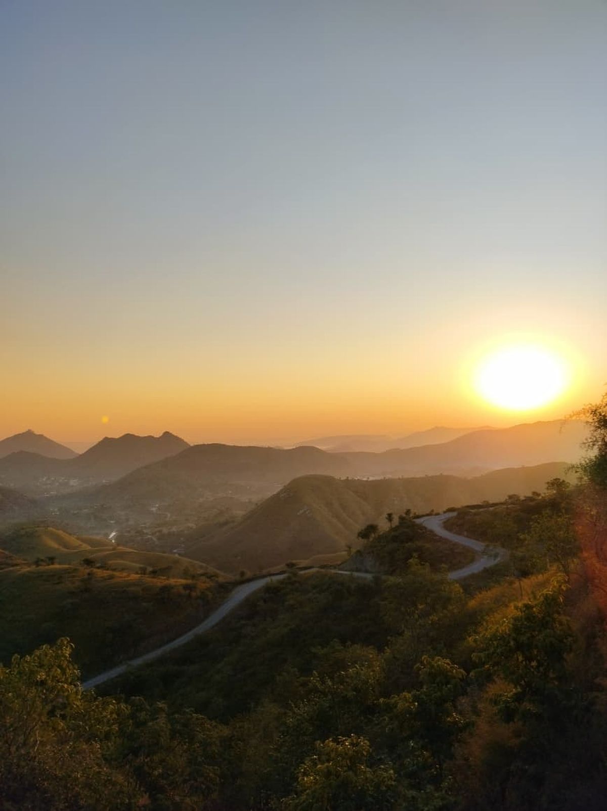 Carretera sinuosa entre las colinas Aravalli al atardecer, Udaipur, India.