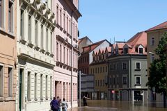 Street view of a flooded European city with people wading through water.