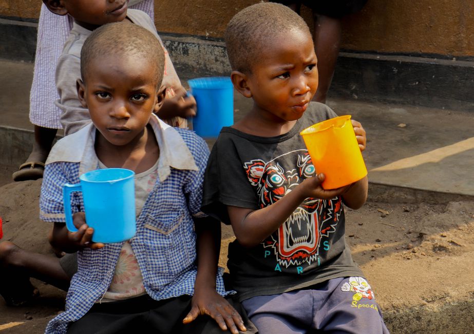 Young children holding colorful cups, enjoying a drink while seated outside. Captures innocence and community.