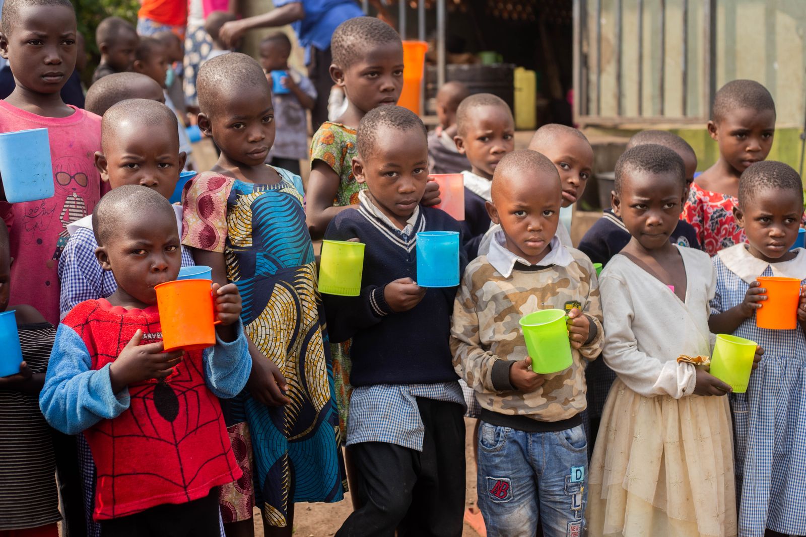 African children holding colorful cups outdoors, reflecting GLAF's community programmes