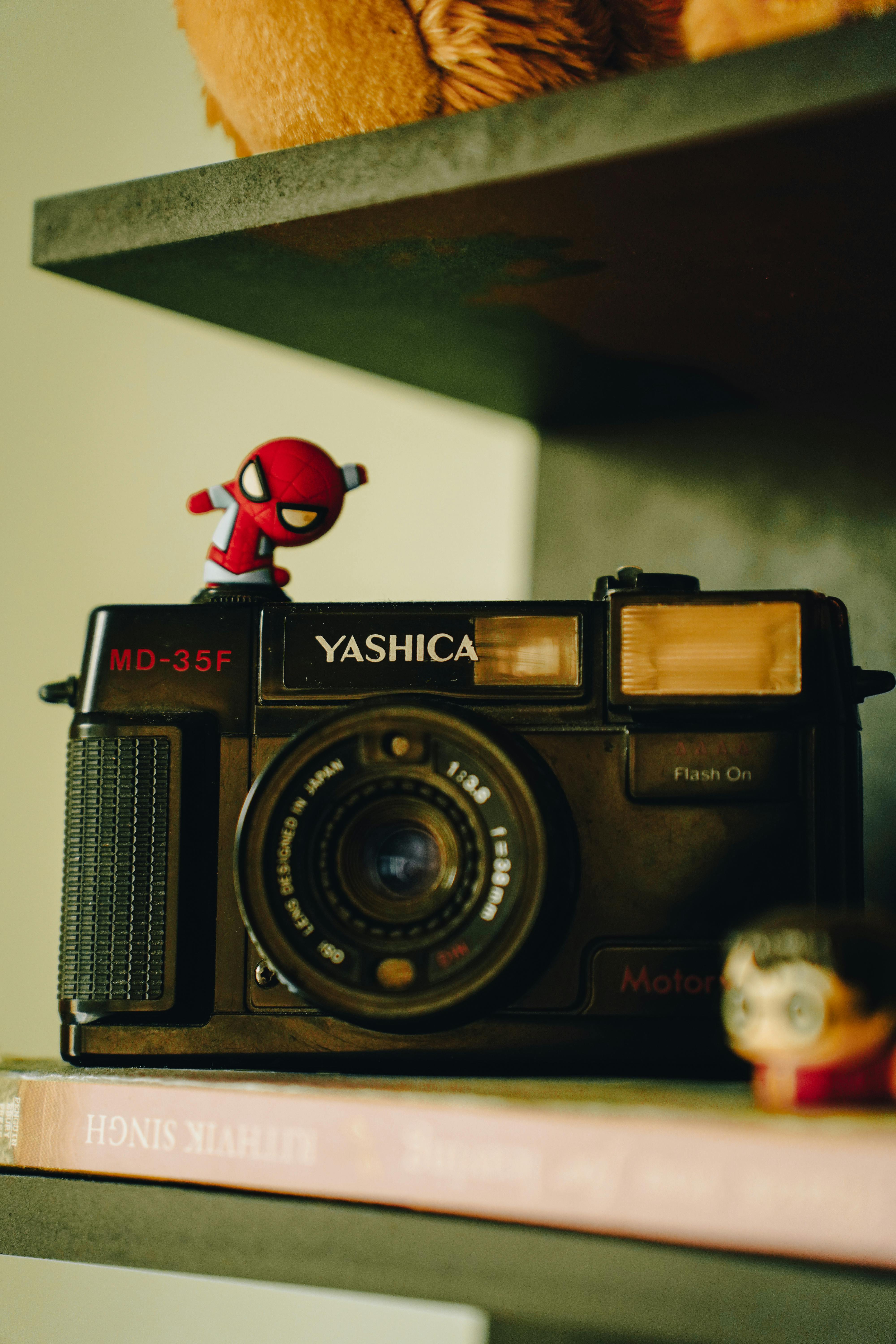 A retro Yashica MD-35F camera displayed with small toy figures, showcasing nostalgia.