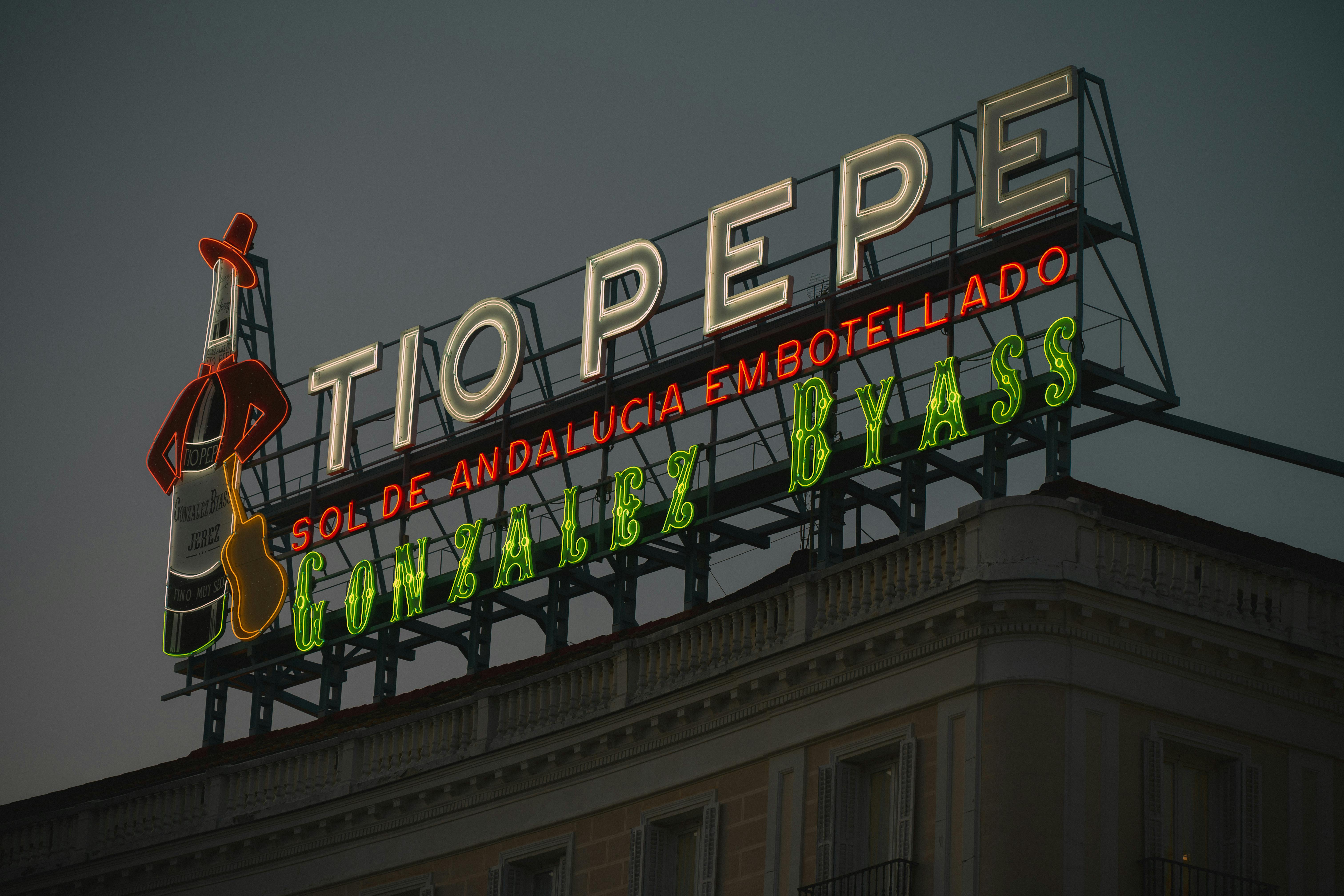 Neon Tío Pepe sign glowing in Madrid during twilight, representing Spanish culture. - Isla del Sol