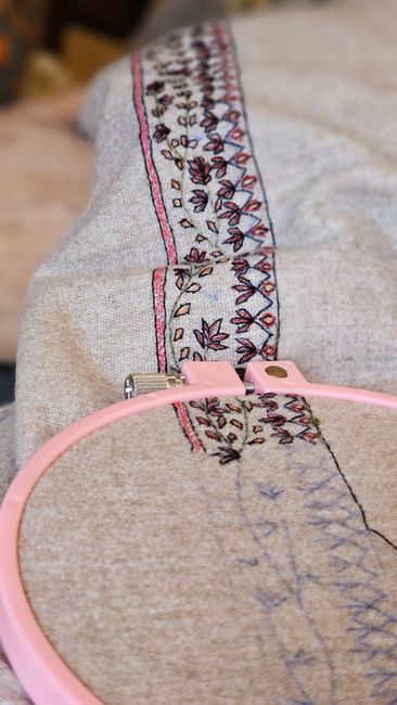 Detailed embroidery pattern on beige fabric secured in a pink hoop, showcasing craftsmanship. - common mistakes buying ladies handbags online Pakistan