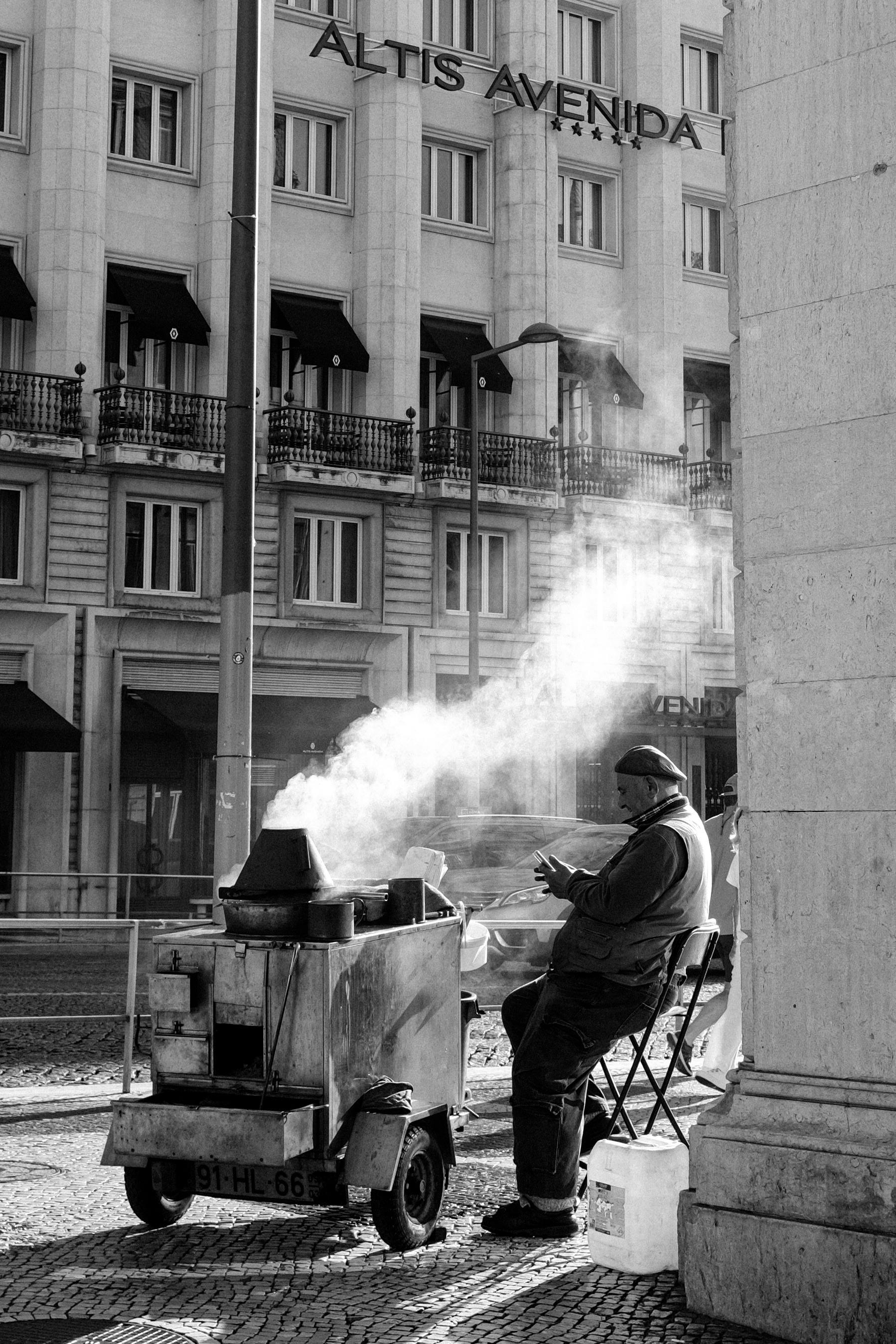 Monochrome image of a street vendor roasting chestnuts in Lisbon.