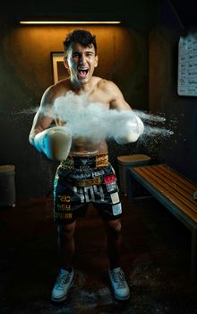 Energetic boxer with gloves, training in a gym with a dramatic burst of powder.