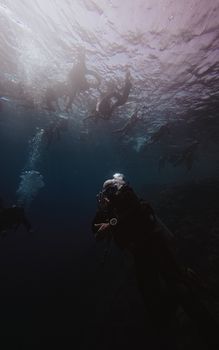 A group of divers immersed in the deep blue ocean, surrounded by bubbles and marine life.