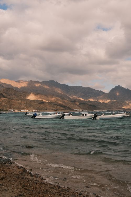Free Scenic view of boats on a lake with mountains in the background and a cloudy sky. Stock Photo