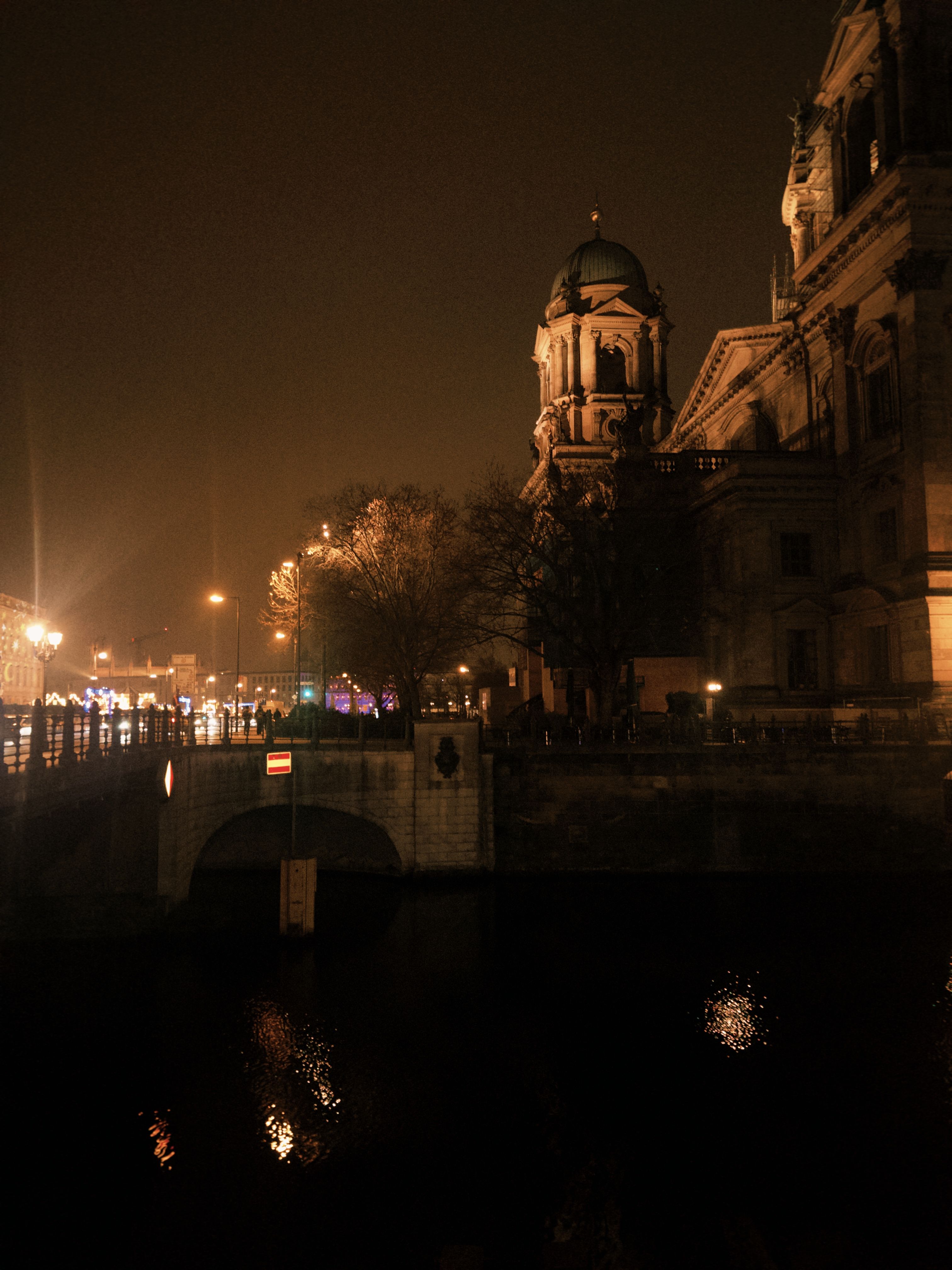Dramatic night view of a historic cathedral by the river, reflecting warm lights.