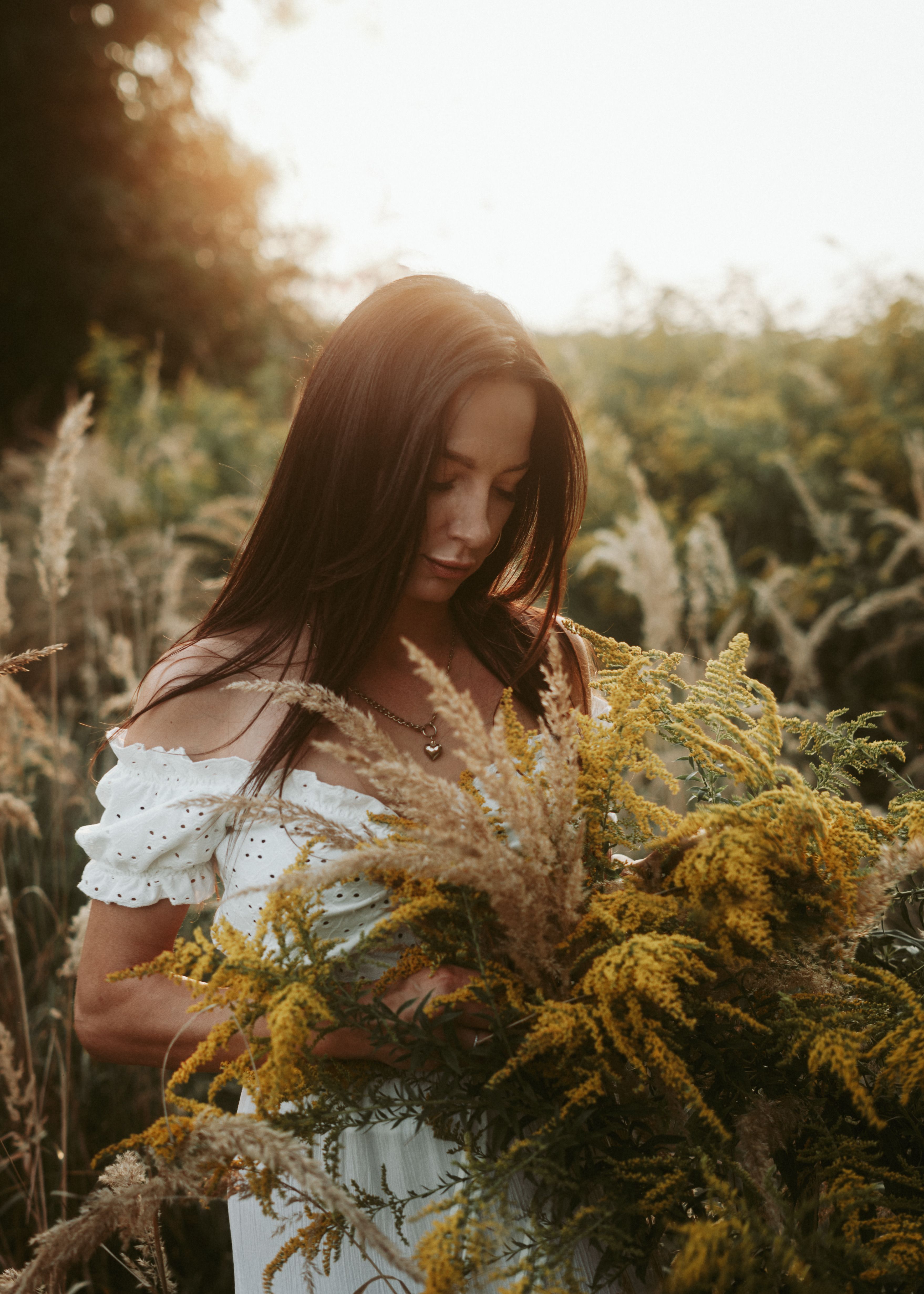 A tranquil scene of a woman holding wildflowers in a sunlit meadow.