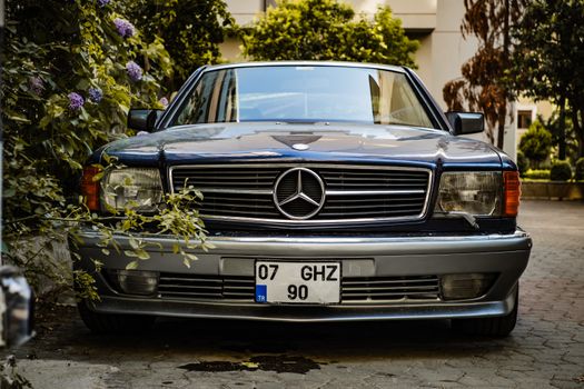Front view of a classic vintage Mercedes-Benz sedan parked outdoors with foliage around.