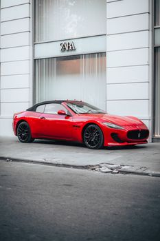 Stylish red convertible parked in city street with Zara store in background, chic urban scene.